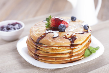 Delicious sweet American pancakes on a plate with fresh fruits