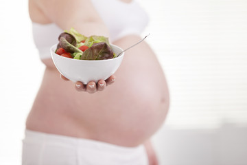 Pregnant woman holding a bowl of fresh salad