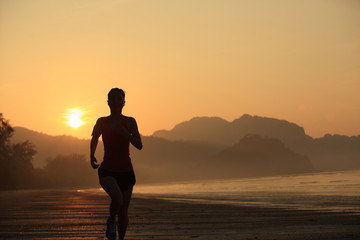 Fototapeta premium young woman running on sunrise beach