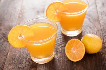 Orange juice in glass, fresh fruits on wooden background