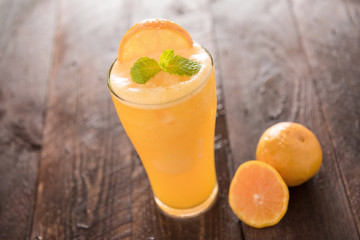 Orange juice in glass, fresh fruits on wooden background