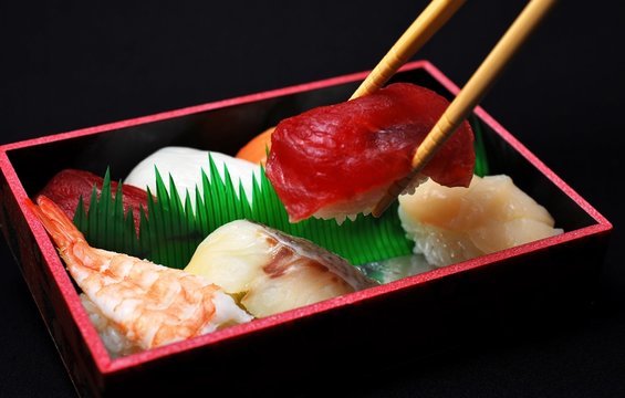 寿司弁当から箸でマグロをつまむ