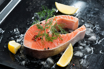 Fresh salmon steak with dill and lemon on ice