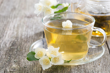Glass cup of green tea with jasmine on wooden background