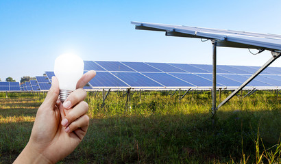 Solar energy panels and Light bulb in hand, Green energy concept