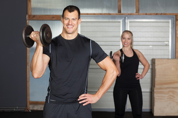 Cross fit - couple in a gym doing exercise with barbell