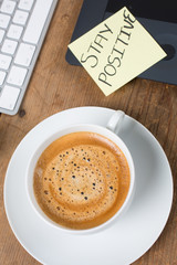 Cup of delicious coffee with computer keyboard on a rustic table