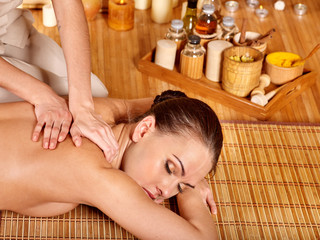 Fototapeta na wymiar Young woman getting massage in bamboo spa.