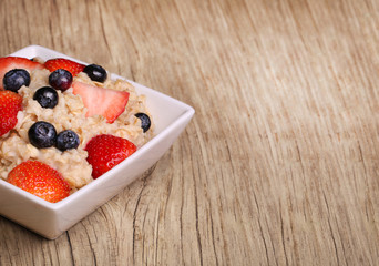 Oatmeal with berries on wooden background