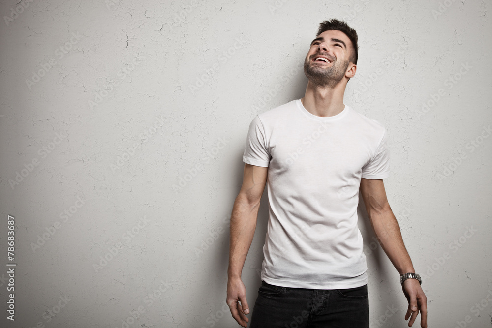 Wall mural smiling man in blank t-shirt, white grunge wall background