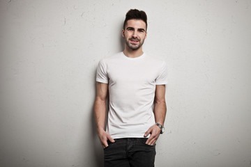 Young man in blank t-shirt, white grunge wall background