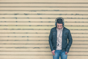 Young handsome man with headphones posing in the city streets