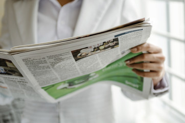 Business person reading newspaper in office