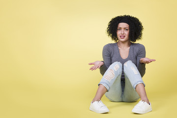 Young woman with questioning look isolated on yellow background. - obrazy, fototapety, plakaty