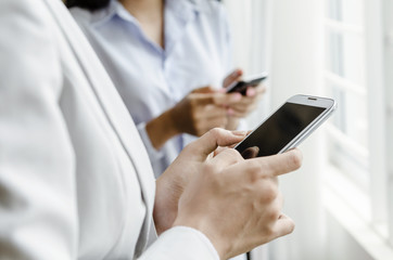 Businesswomen using smart phone in front of window