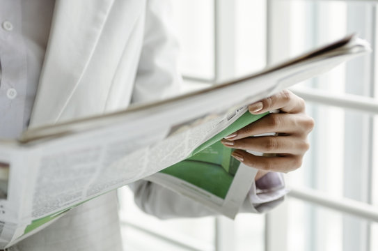 Closeup of businesswoman hand holding newspaper