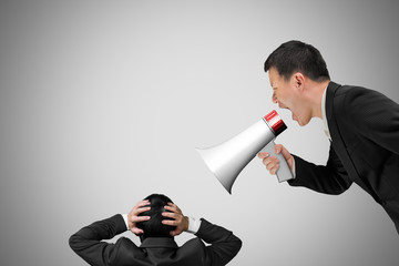 Boss using megaphone yelling at his employee with concrete wall