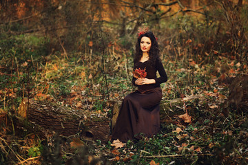 mysterious lady is sitting in autumn forest at sunset