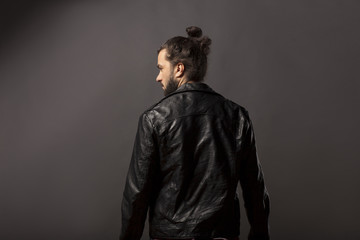 back view of man with beard and bun in black leather jacket