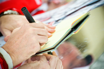 closeup of an unknown celebrity signing autographs