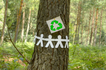 Recycle sign with paper men on a tree