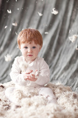 Baby Newborn with feather. Child Sitting at feathers pile and ca