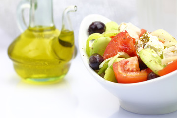 Bowl with fresh salad and olive oil on tabletop