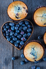 Blueberry muffins and fruit heart on wooden table from above