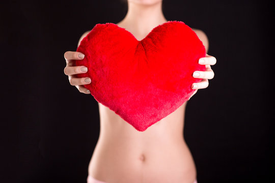 Closeup image of a woman holding red heart over black background