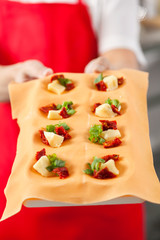 Midsection Of Chef Holding Tray With Stuffed Ravioli Pasta Sheet