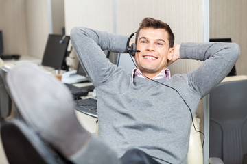 Relaxed Smiling Customer Service Representative With Legs On Des