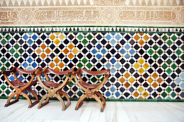 Chairs and the wall of tiles in The Alhambra, Granada, Spain
