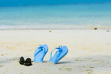 Fototapeta na wymiar blue slippers and sunglass on the beach