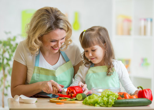 mom and her daughter preparing vegetables at kitchen