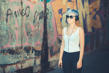 Obraz na płótnie Canvas young beautiful short blue hair hipster woman with headphones mu