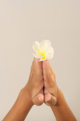 Close-up of female hands in oil holding flower on beige