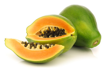 fresh papaya fruit and a cut one on a white background