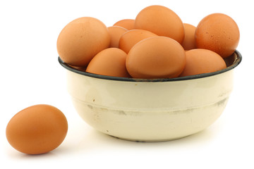 brown eggs in an enamel bowl on a white background