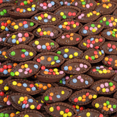 Obraz na płótnie Canvas chocolate cookies sprinkled with colorful dragees as background