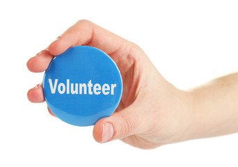 Round volunteer button in hand isolated on white