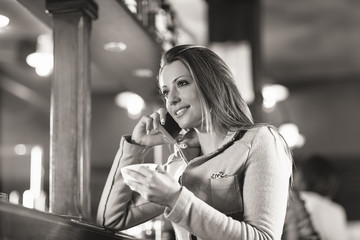 Smiling woman at the bar having a phone call