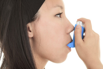 Close up image of a young woman using inhaler for asthma. White