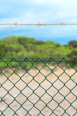 Fence with barbed wire under blue sky.