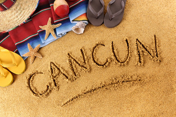 Cancun beach writing word written in sand on a mexico beach with sombrero and traditional blanket photo