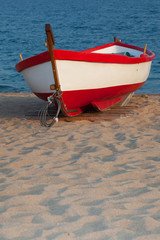 White with red stripe boat on the beach.