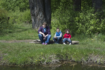 Spring on the shores of mother with children sitting on a log.