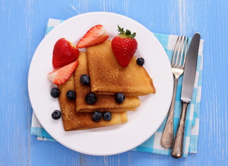 Stack of pancakes, fresh strawberry blueberry, cutlery
