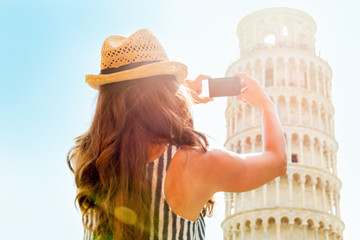 Young woman taking photo of leaning tower of pisa, tuscany - obrazy, fototapety, plakaty
