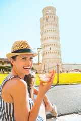 Portrait of happy woman eating pizza in front of tower of  pisa