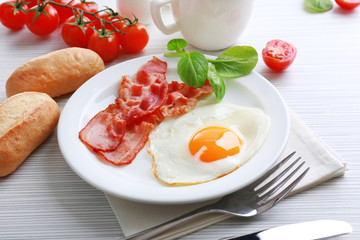 Bacon and eggs on color wooden table background